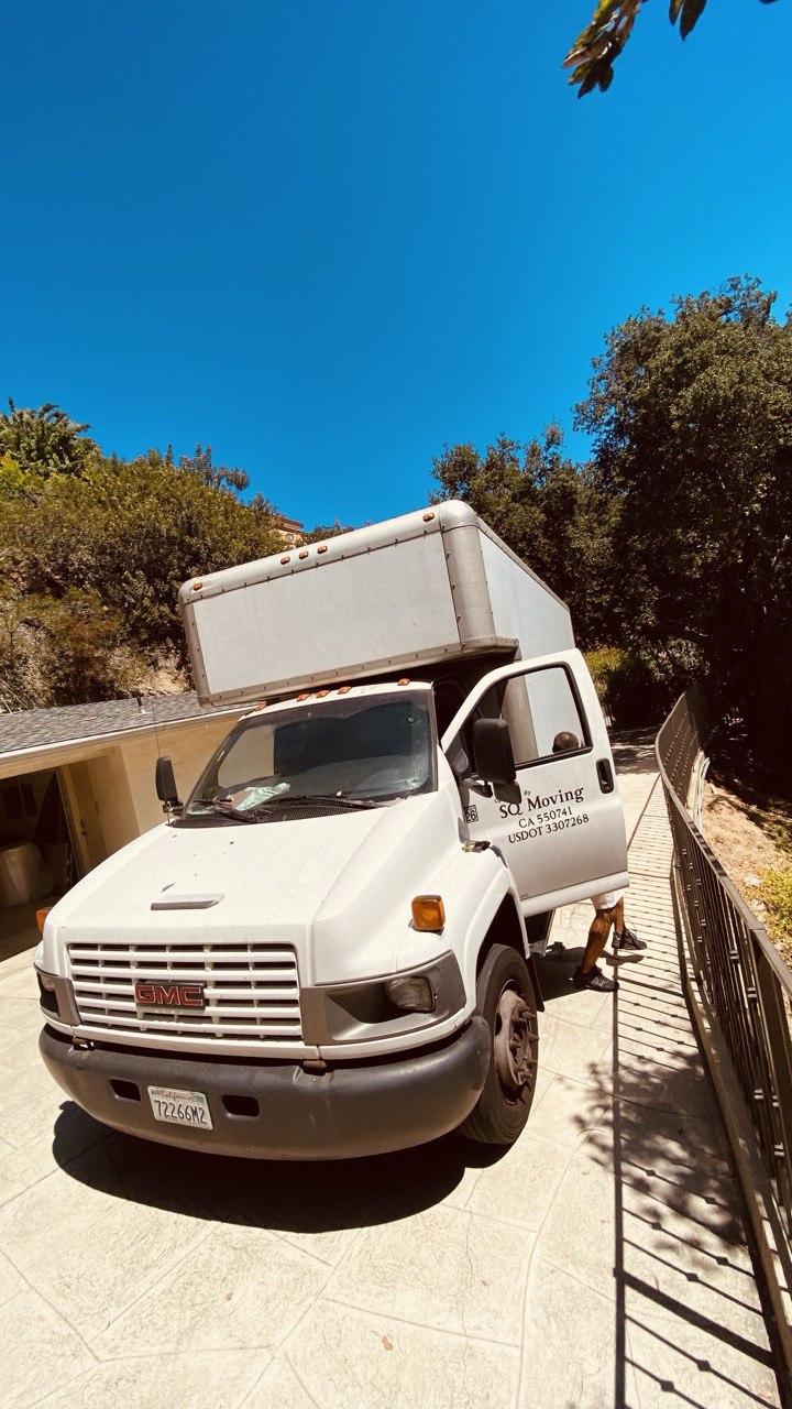 Moving truck in Agoura Hills, CA parked on a residential street while professional movers load carefully wrapped furniture and boxes.