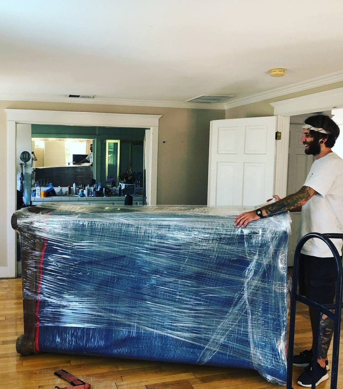 Agoura Hills moving company crew carefully packing a large wooden armoire with moving blankets and shrink wrap during a residential move.