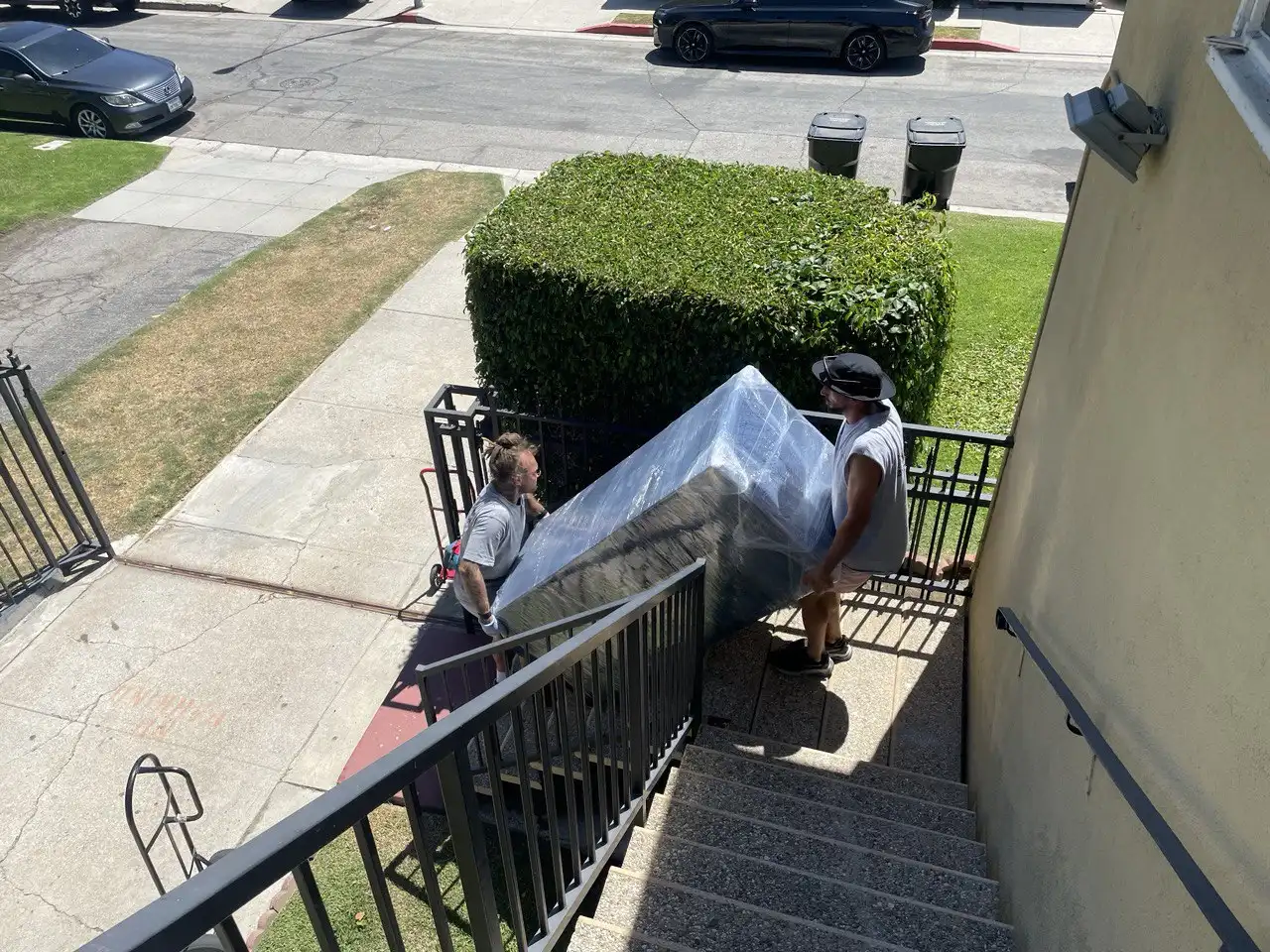 Movers in Sierra Madre performing heavy lifting, carrying a refrigerator up an outdoor staircase