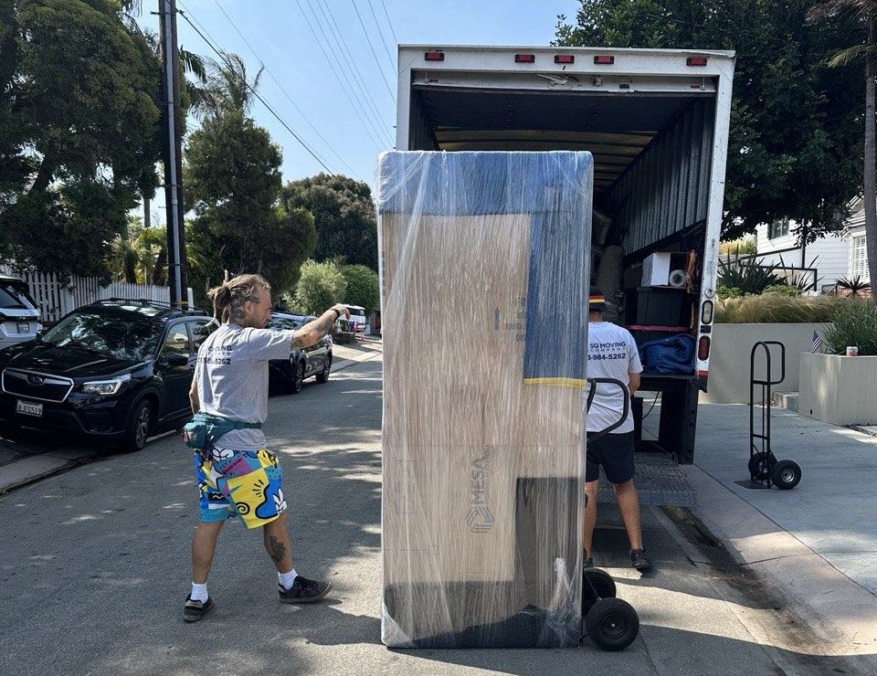 Movers in Mid City loading a large dresser into the moving truck.