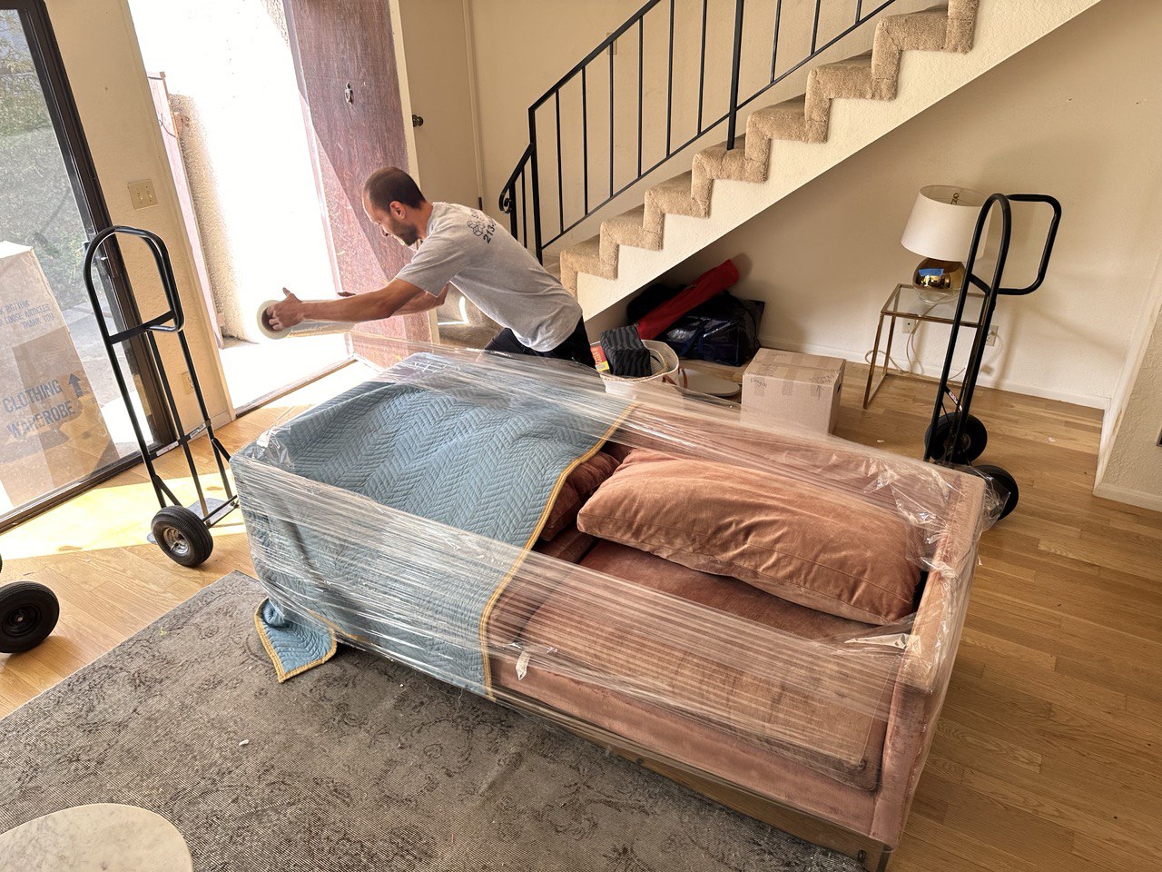 SQ Moving Company mover packing a couch with shrink wrap in a Palms apartment 2025.