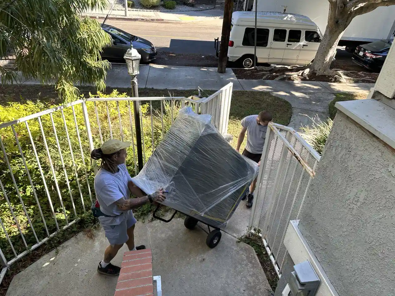 Professional Marina del Rey movers transporting a wrapped dresser up the stairs during a residential move