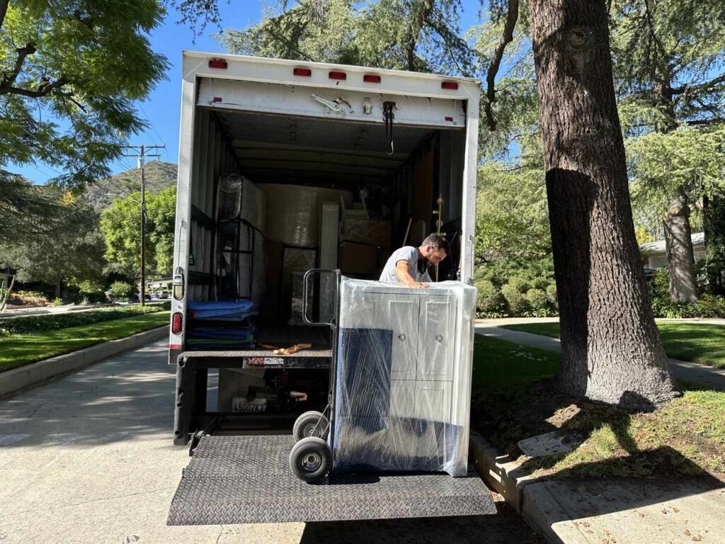 Certificate of Insurance for Moving: What You Need to Know 7 SQ Moving Company crew loading a fully wrapped cabinet into the moving truck in a residential neighborhood.