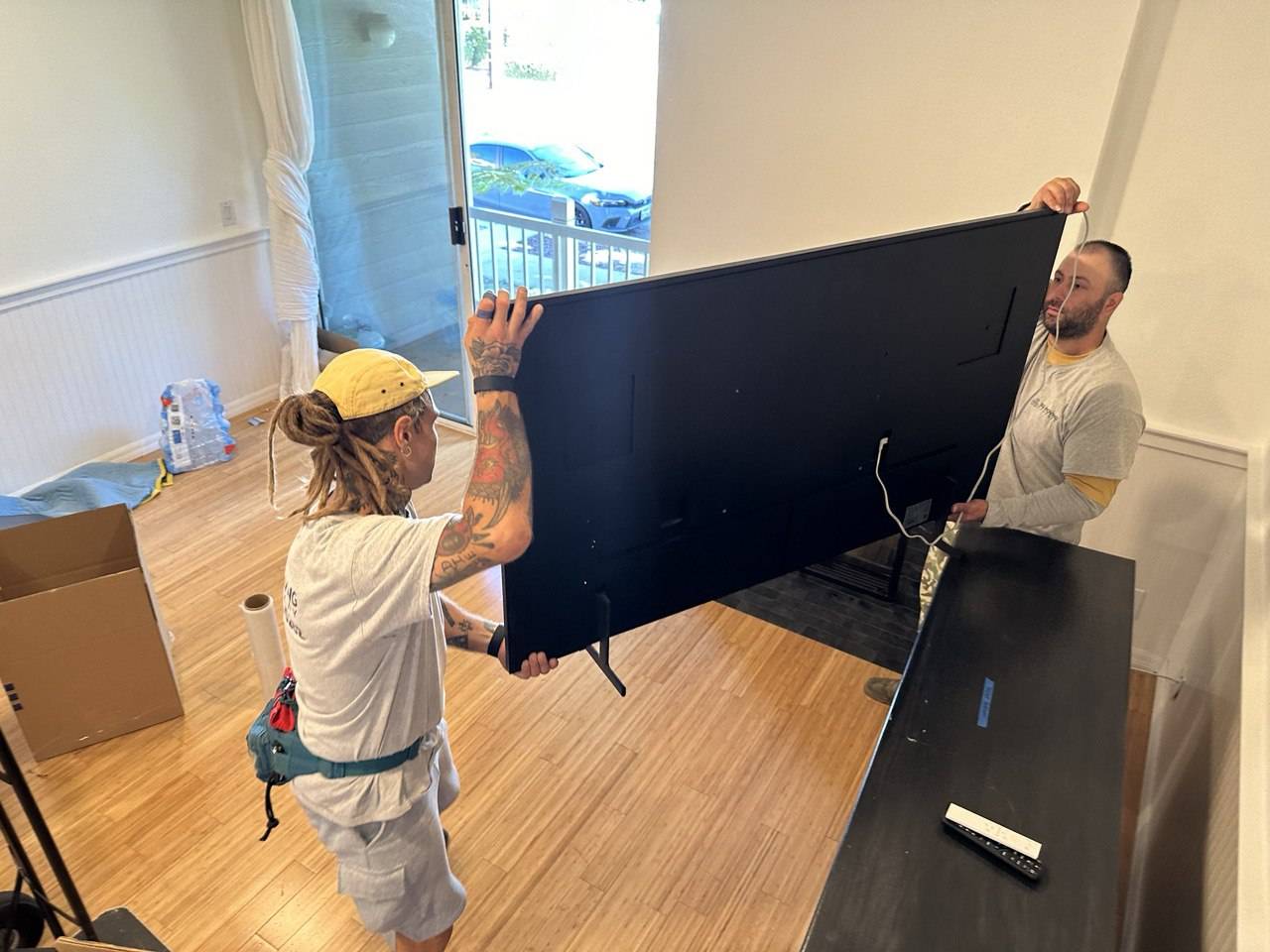 Professional Palms movers wrapping and preparing a flat-screen TV for secure transport.