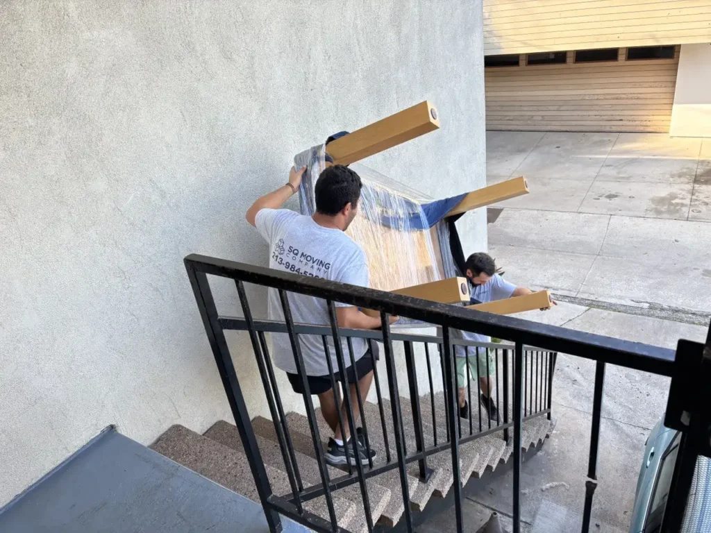 How to Prepare Furniture for Moving in LA: Step-by-Step Guide 12 Team lifting of heavy dining table by the stairs in Long Beach, CA.
