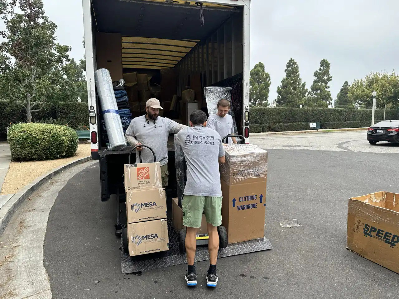 SQ Moving Company crew loading packed boxes and wardrobe cartons into a moving truck during an apartment move in Westwood, CA