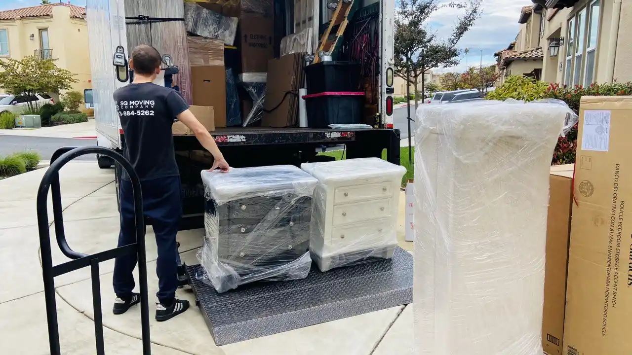 SQ Moving Company crew loading two fully wrapped nightstands and a tall dresser onto a moving truck liftgate during a Brentwood house relocation