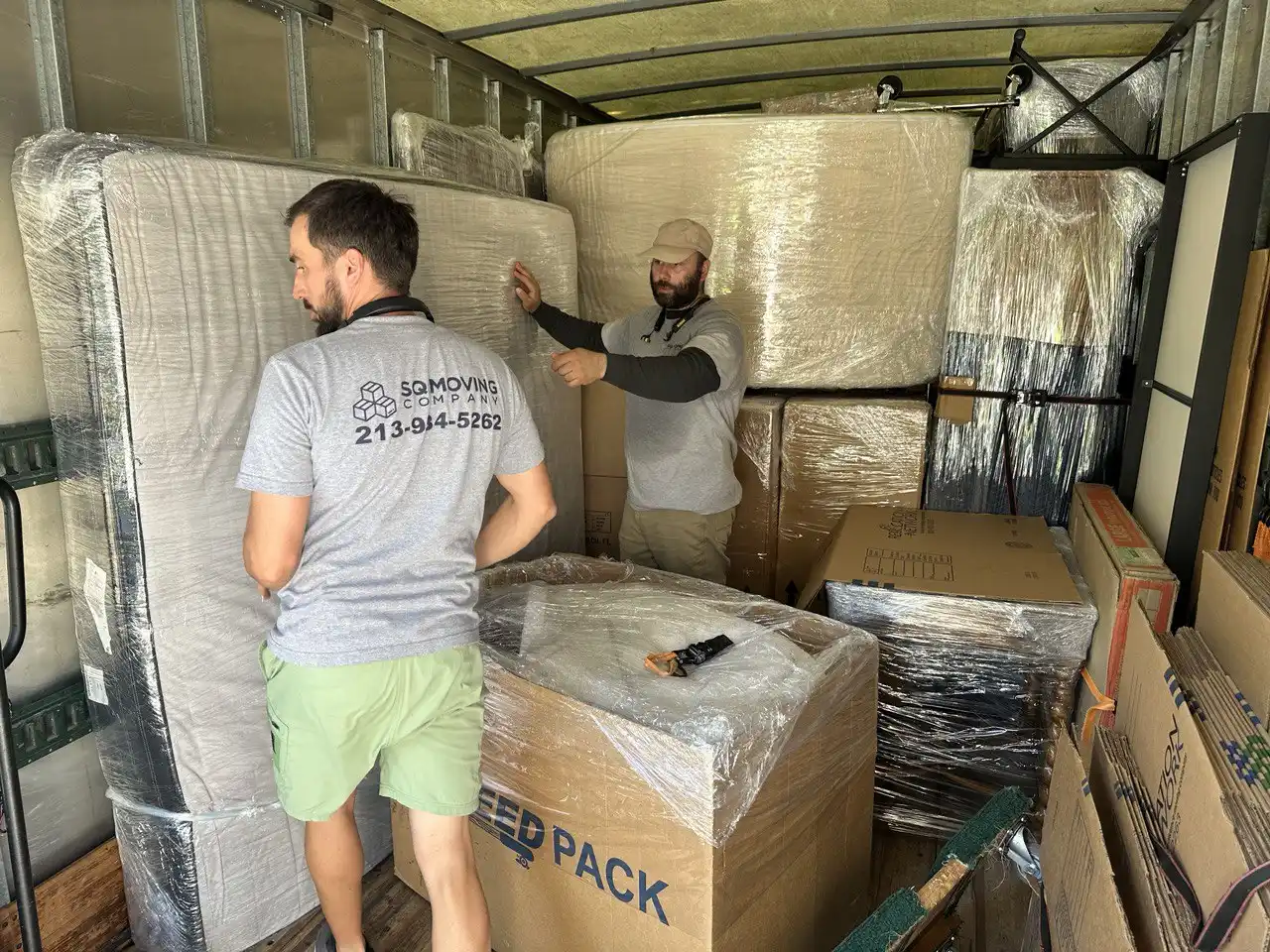Downtown Los Angeles movers from SQ Moving Company loading a fully wrapped mattress and boxes into a moving truck