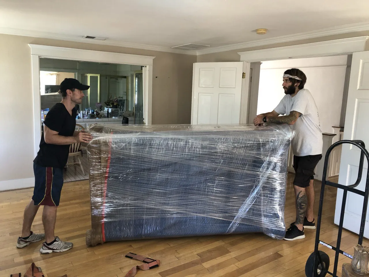 Downtown Los Angeles movers carefully wrapping and moving a large piece of furniture inside a office