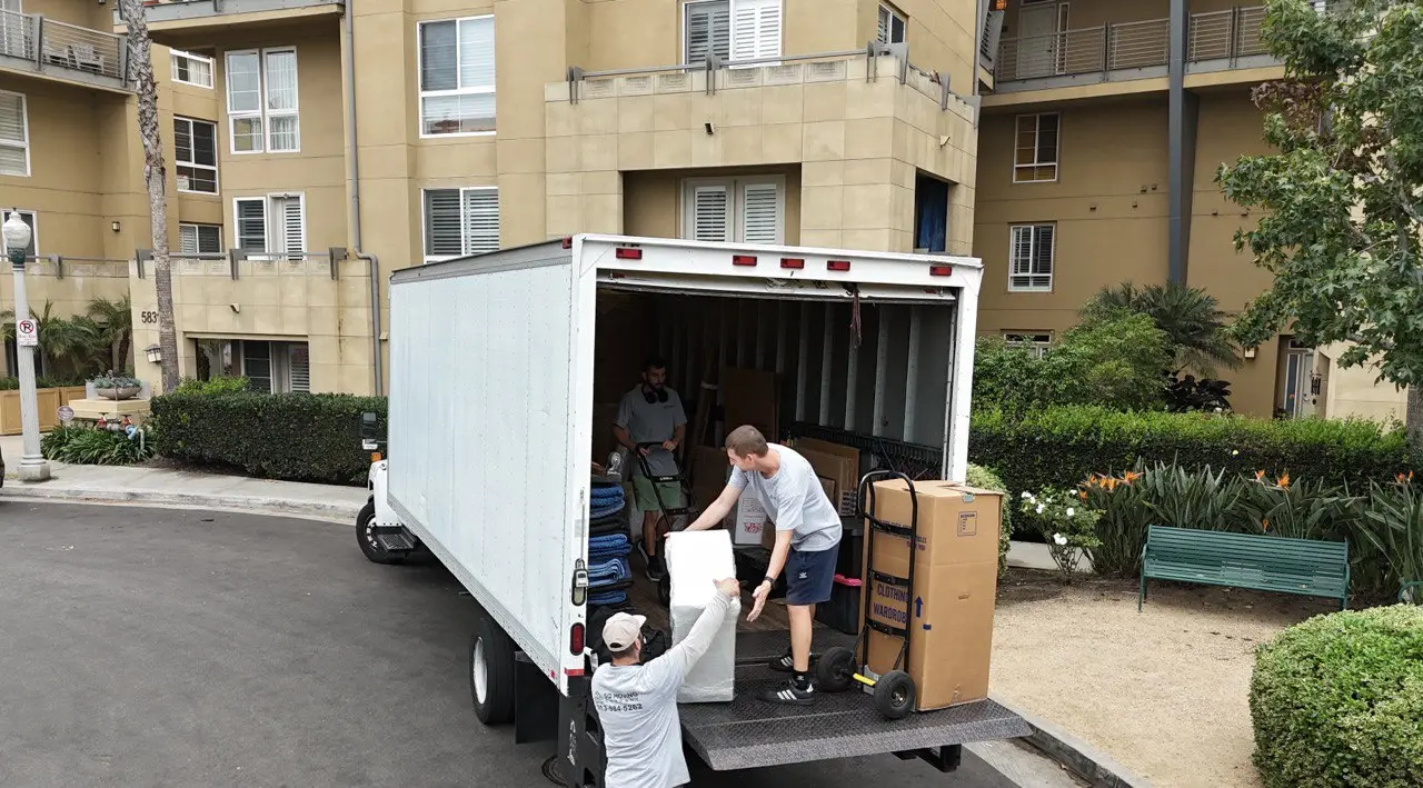 Downtown Los Angeles movers loading boxes and furniture into a moving truck outside a modern apartment building in DTLA