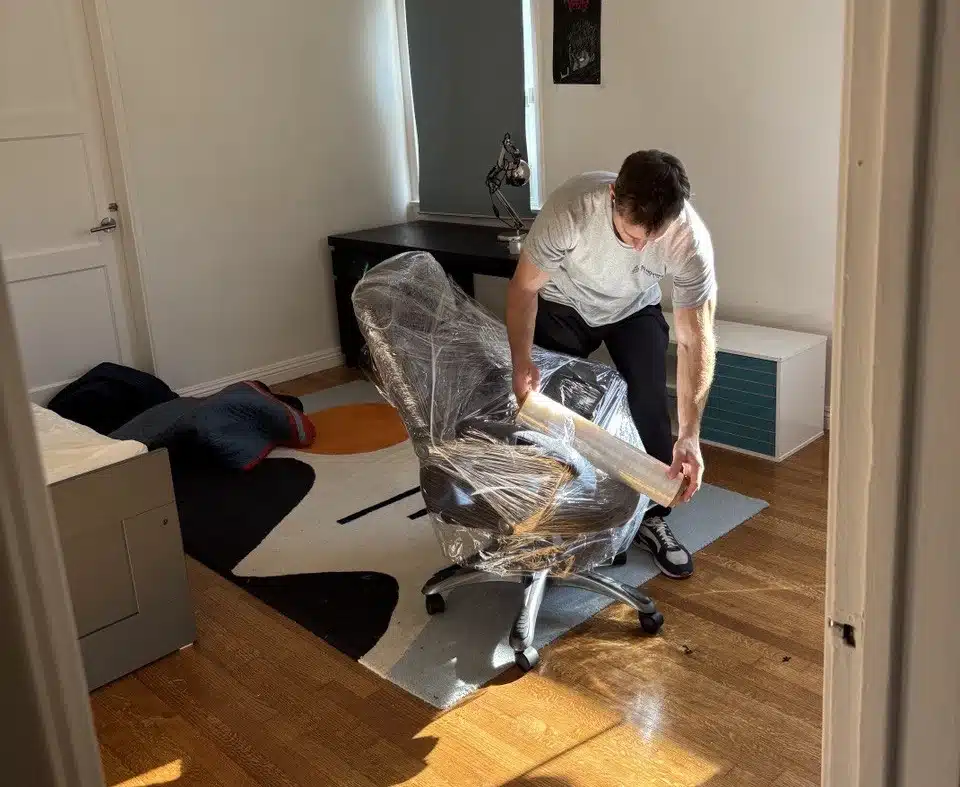 San Pedro movers from SQ Moving Company carefully loading a large wrapped appliance onto a moving truck on a residential street