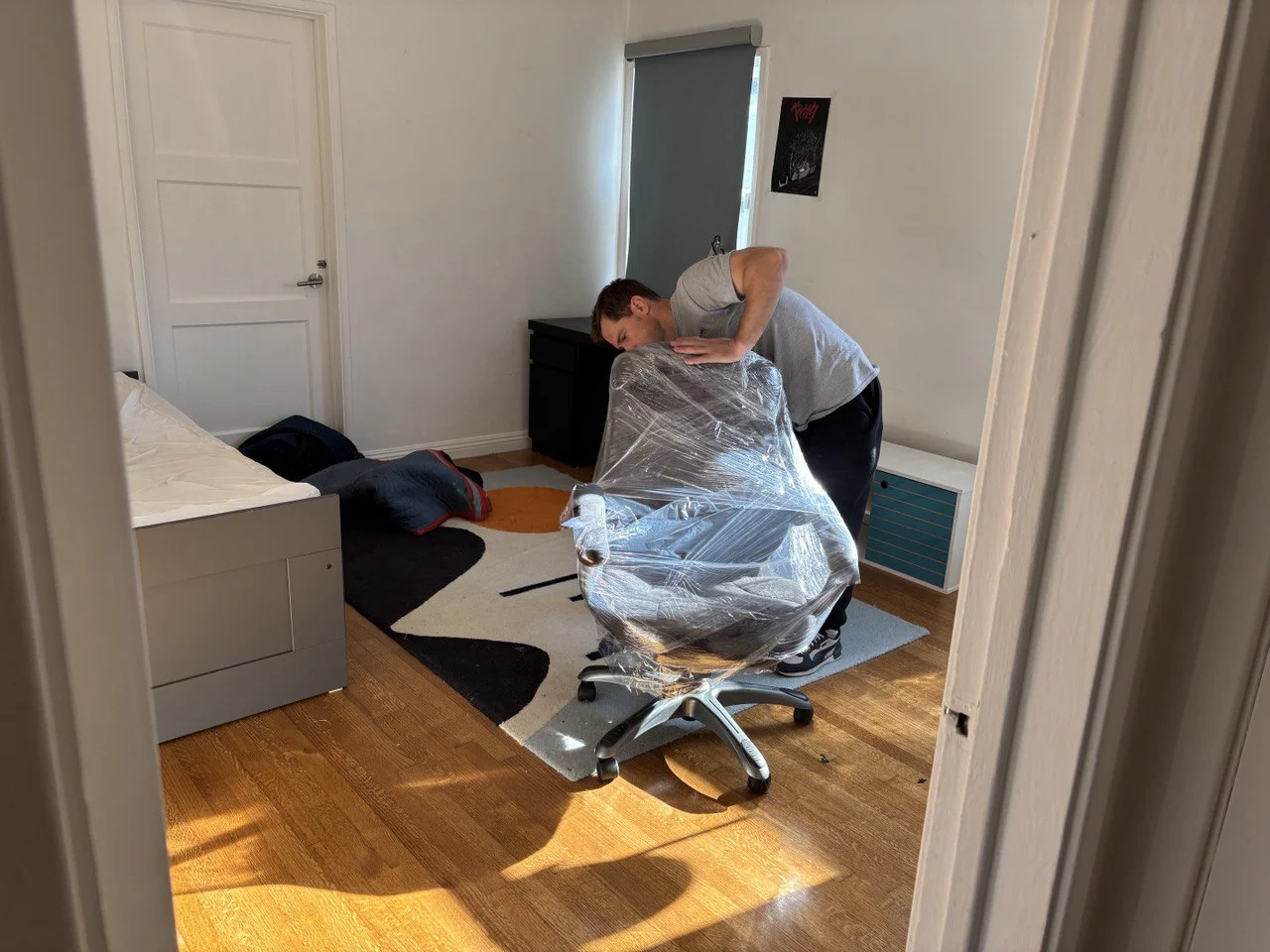 SQ Moving Company mover wrapping an office chair in plastic for protection during a bedroom move in Century City